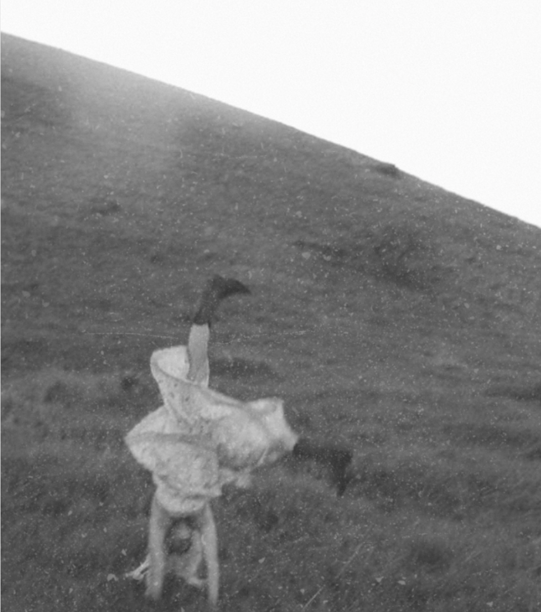 Girl in cowboy boots cartwheeling on a hill
